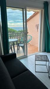 een woonkamer met een bank en een balkon met een tafel bij Lumineux studio vue mer in Sainte-Maxime +5 foto's