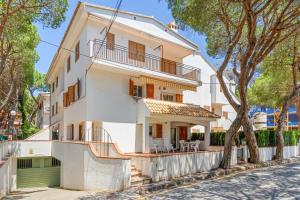 ein weißes Haus mit einem Baum davor in der Unterkunft WELCS APARTAMENTO 165 PDA con piscina in Platja  d'Aro