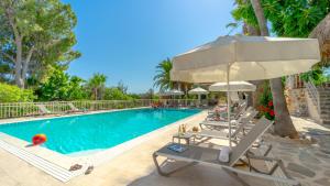 a swimming pool with lounge chairs and an umbrella at Golden Lighthouse Hotel in Patara