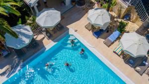 an overhead view of people in a swimming pool with umbrellas at Golden Lighthouse Hotel in Patara