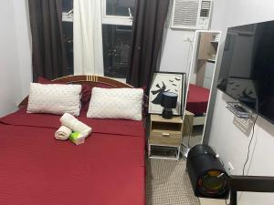 a bedroom with a bed with red sheets and a window at Pierrecondotel in Manila