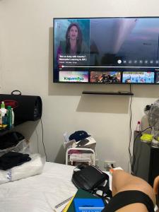 a person laying on a bed in front of a tv at Pierrecondotel in Manila