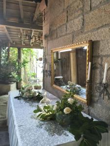 a table with flowers and a mirror on a wall at Casa d'Aldeia de Souto de Lafões OLIVEIRA DE FRADES in Oliveira de Frades +35 photos