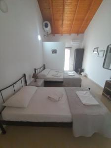 two beds in a room with white walls and wooden ceilings at Sofia's Rooms in Himare