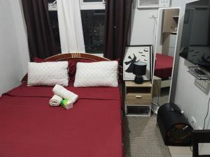 a bedroom with a red bed with two pillows at Nicecondote in Manila
