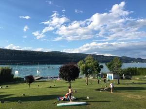 フェルデン・アム・ヴェルターゼーにあるSweet little home am Wörtherseeの水の近くの公園内の一団