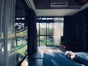 a bedroom with a bed and a large window at BREATHE - Rice Valley in Ban Pa Lan