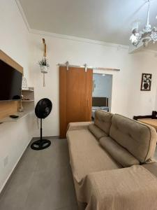 un salon avec un canapé et une télévision dans l'établissement Apartamento Confortável Perto da Praia, à Cabo Frio