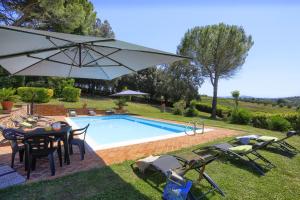 une piscine avec une table, des chaises et un parasol dans l'établissement Villa Orsini Peccioli - Villa storica ad uso esclusivo con piscina, à Peccioli