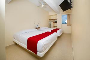 a bedroom with two beds with red and white sheets at Mishol Bodas Hotel & Beach Club Acapulco Diamante in Acapulco