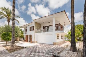 a white house with palm trees in front of it at Villa Paraíso - Piscina Playa Barbacoa Wifi in San Juan de Alicante