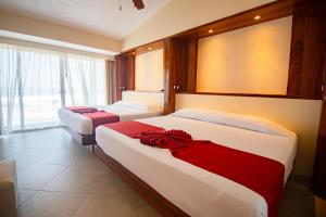 a bedroom with two beds with red and white at Mishol Bodas Hotel & Beach Club Acapulco Diamante in Acapulco