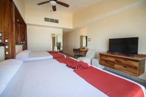 a bedroom with two beds and a flat screen tv at Mishol Bodas Hotel & Beach Club Acapulco Diamante in Acapulco +55 photos