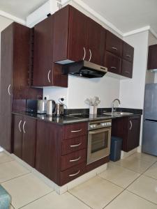 a kitchen with wooden cabinets and a stove top oven at Accommodation Front - Ocean View 2 Sleeper in Durban +12 photos