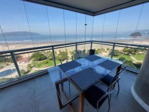 a table and chairs in a room with a view of the beach at Book Santos - Unlimited 901 - Frente Mar com Vista Panorâmica in Santos