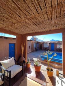 un patio con divano, piante in vaso e piscina di Hostal Lackuntur a San Pedro de Atacama