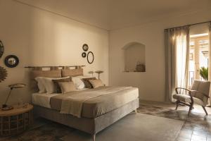 a bedroom with a large bed and a chair at Dimora Santagatha in Noto