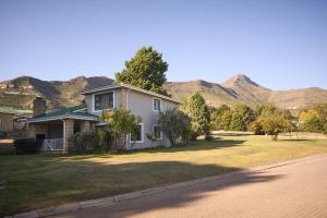 a house on a street with mountains in the background at Villa Mohau 178 in Clarens