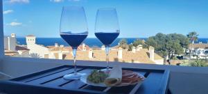 due bicchieri di vino e un piatto di cibo sul balcone di Appartment Urbanizacion Duquesa Suites Golf and Garden Beautiful View a Manilva
