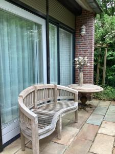 eine Holzbank auf einer Terrasse mit einem Tisch in der Unterkunft HeijenLUXE VAKANTIEWONING in Heijen
