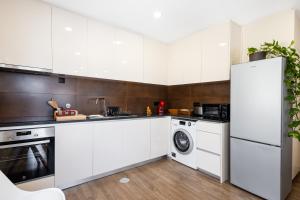 a kitchen with white cabinets and a washer and dryer at Pontes Guest House in Arcozelo