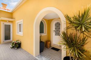 an arched entryway to a yellow house with plants at Pontes Guest House in Arcozelo