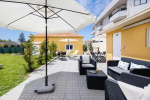 a patio with two couches and an umbrella at Pontes Guest House in Arcozelo