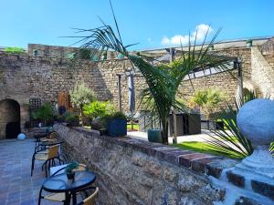 a patio with tables and chairs and a brick wall at Chambres d'hôtes Les Carmélites in Guingamp