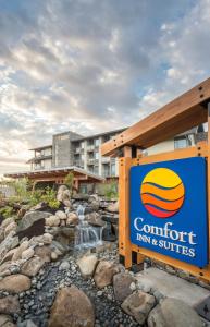 um sinal para estalagem e suites confortáveis ao lado de uma cascata em Comfort Inn & Suites em Campbell River