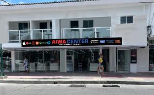a woman walking in front of a white building at APARTAHOTEL BEIRUT INN in San Andrés