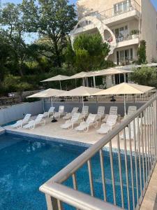 a swimming pool with lounge chairs and umbrellas next to a building at Most Oliva Resort Budva in Budva +119 photos