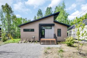 a small house with a black roof at Achille - Boisé avec spa et sauna in Pont-Rouge
