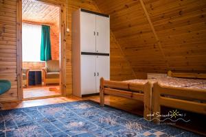 a bedroom with a bed in a wooden cabin at Domki Letniskowe NAD ŚNIARDWAMI BARBARA MAJKRZAK in Nowe Guty