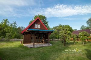 a small house with a red roof in a yard at Domki Letniskowe NAD ŚNIARDWAMI BARBARA MAJKRZAK in Nowe Guty