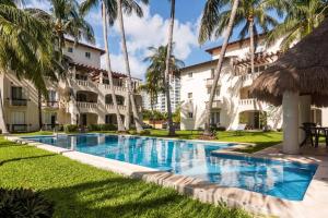 a swimming pool in front of a building with palm trees at Stunning condo in excellent location in Cancún