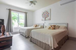 a white bedroom with two beds and a window at Stunning condo in excellent location in Cancún +35 photos