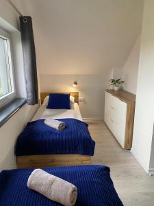 a bedroom with two beds with blue sheets and a window at Antracytowy Zakątek in Łeba +64 photos