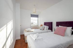 two beds in a room with white walls and a window at Shore House - Pittenweem in Pittenweem