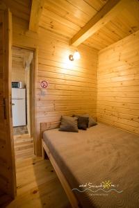 a bedroom with a bed in a wooden cabin at Domki Letniskowe NAD ŚNIARDWAMI BARBARA MAJKRZAK in Nowe Guty