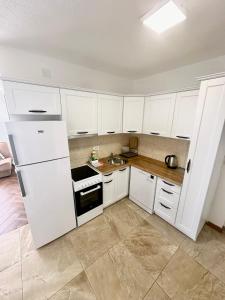 a kitchen with white cabinets and a white refrigerator at Montenegrina Apartment in Budva