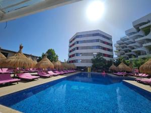 a swimming pool with chairs and umbrellas and a building at My home - Unique Luxury in Năvodari