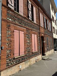 a brick building with pink doors on the side of it at Le Gallilée - Studio Climatisé Calme Centre-Ville in Toulouse