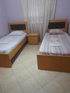 two twin beds in a room with a tiled floor at Tina's Apartment in Gjirokastër