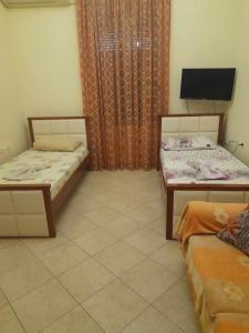 a room with two beds and a tv in it at Tina's Apartment in Gjirokast&euml;r