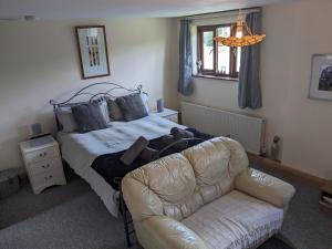 a bedroom with a bed with a teddy bear and a couch at South Barn in Stanningfield