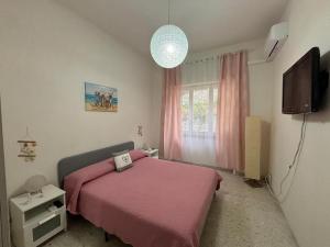 メータにあるCasa Vacanza RosaMatildeのベッドルーム(ピンクベッド1台、テレビ付)