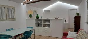 a white kitchen with a glass table and a couch at Casa Giulia in Castelbuono