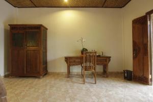 Cette chambre comprend un bureau en bois et une chaise. dans l'établissement Pekak Mangku Guest House, à Ubud