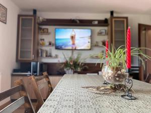 a dining room table with a vase of plants and a television at Вила Рай in Voneshta Voda