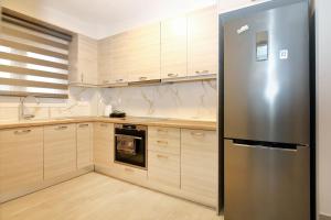 a stainless steel refrigerator in a kitchen with wooden cabinets at Nikiti Cozy Summer Maisonette in Skála Nikíta